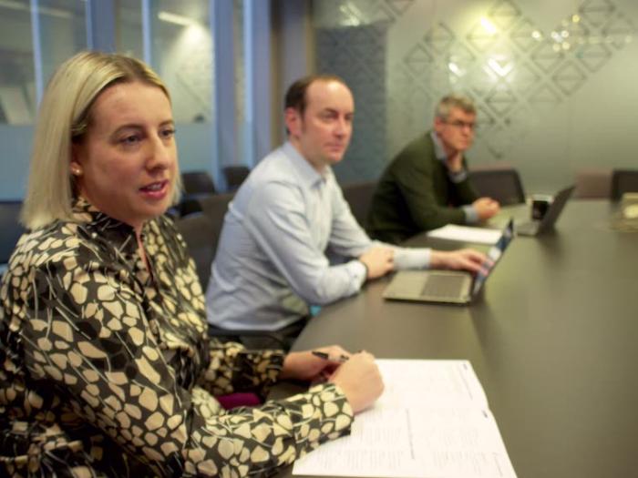 Three people sitting at a boardroom table