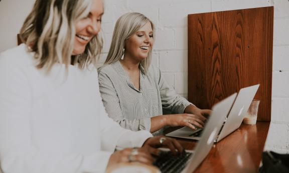 Two women looking at  laptops